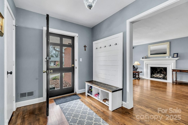 mudroom with a fireplace with flush hearth, wood finished floors, visible vents, and baseboards