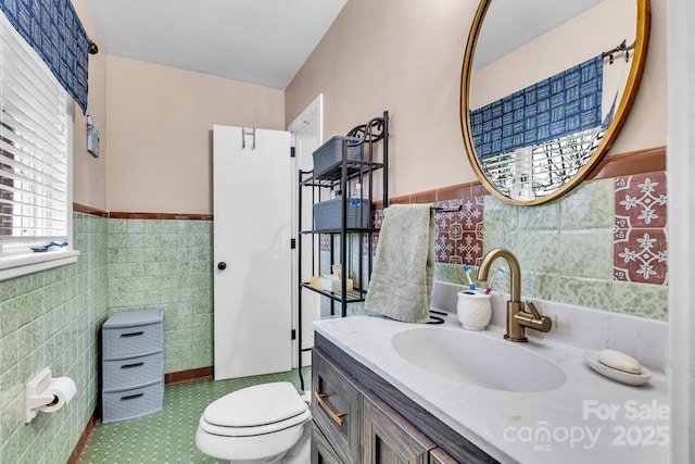 bathroom with a wainscoted wall, toilet, tile walls, and vanity