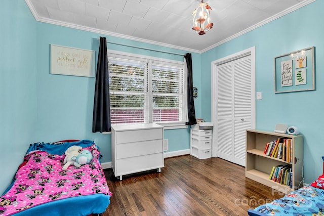 bedroom with a closet, baseboards, ornamental molding, and dark wood-style flooring