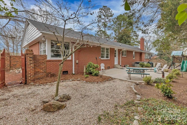 back of property featuring entry steps, a patio, crawl space, brick siding, and a chimney