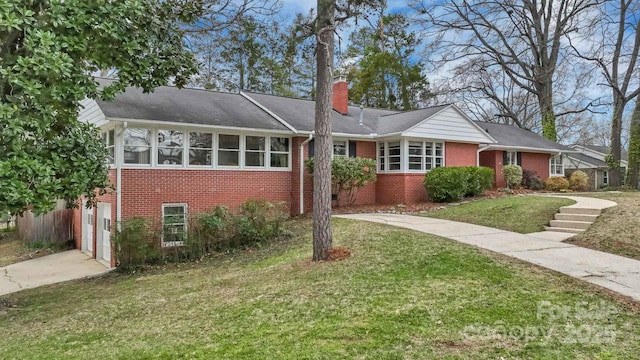 single story home featuring a front yard, driveway, a chimney, a garage, and brick siding