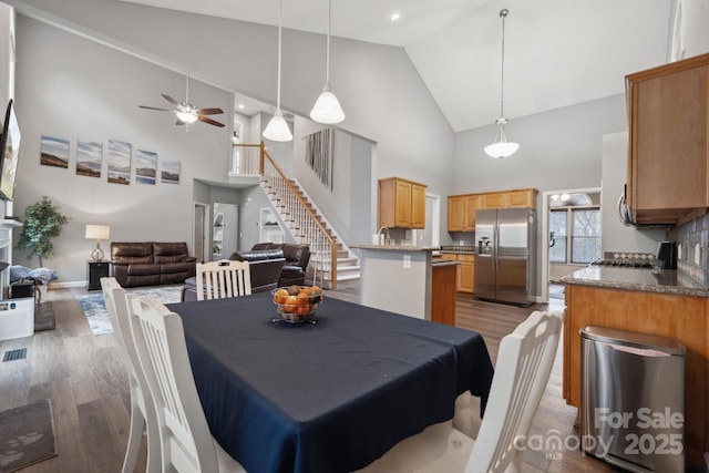 dining area featuring stairway, high vaulted ceiling, light wood-style flooring, and a ceiling fan