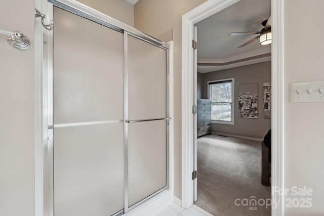 bathroom featuring ceiling fan, baseboards, and a stall shower