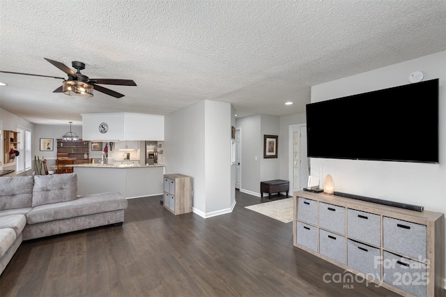 living area with a textured ceiling, baseboards, a ceiling fan, and dark wood-style flooring