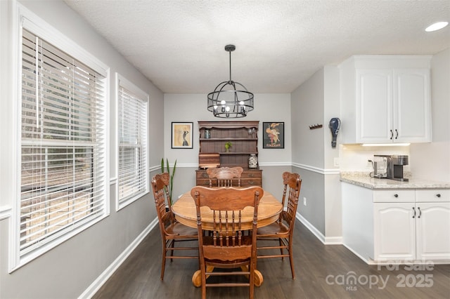 dining space with baseboards, dark wood-type flooring, a chandelier, and a textured ceiling