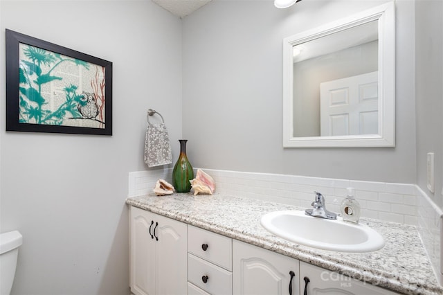 bathroom with tasteful backsplash, toilet, and vanity