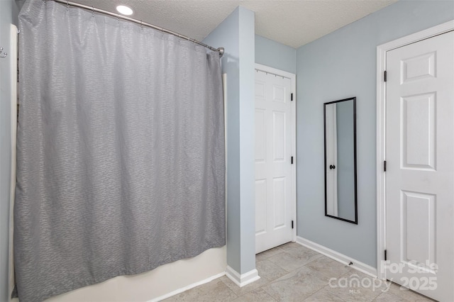 full bathroom featuring a shower with curtain, a textured ceiling, and baseboards