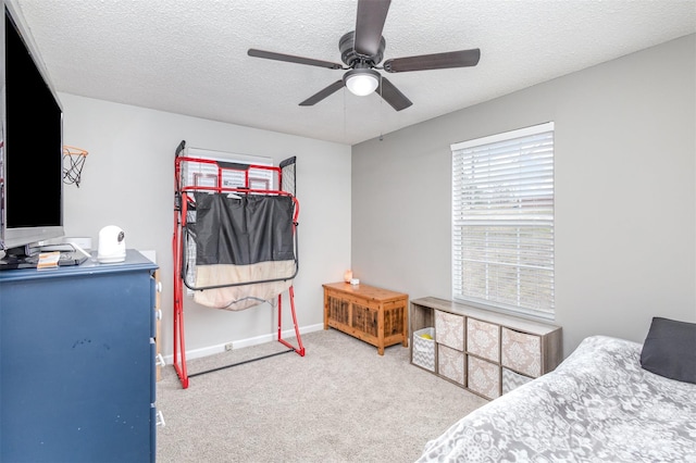 carpeted bedroom featuring a textured ceiling, baseboards, and a ceiling fan