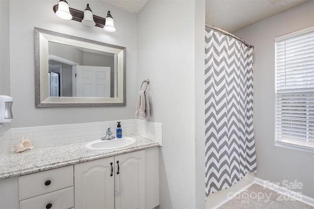 full bathroom featuring a wealth of natural light, a textured ceiling, vanity, and tile patterned floors