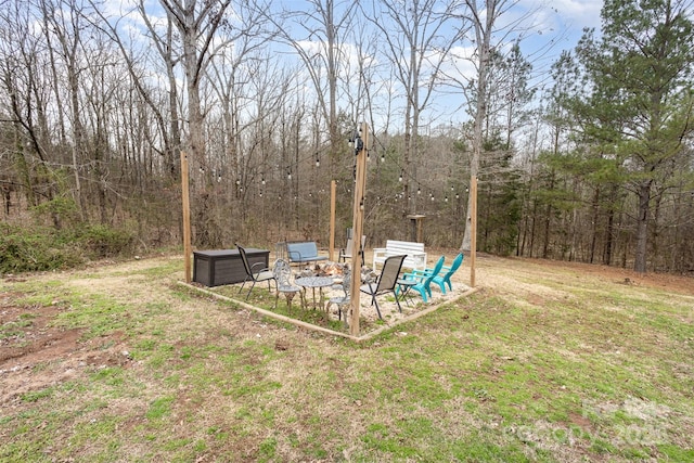 view of yard with a wooded view and an outdoor fire pit