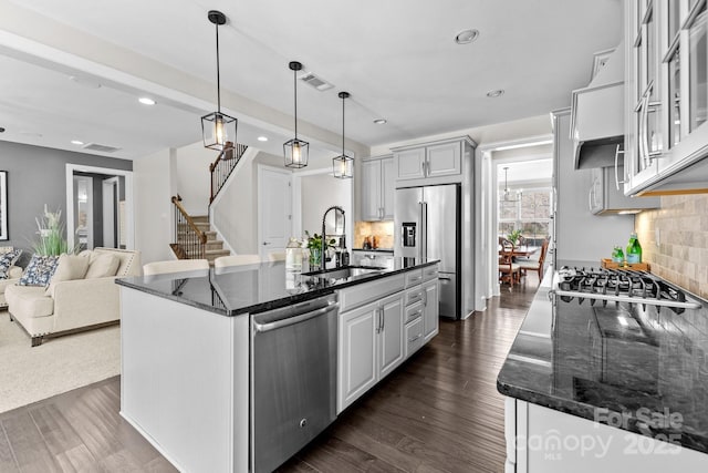 kitchen with visible vents, dark wood-style flooring, a sink, stainless steel appliances, and tasteful backsplash