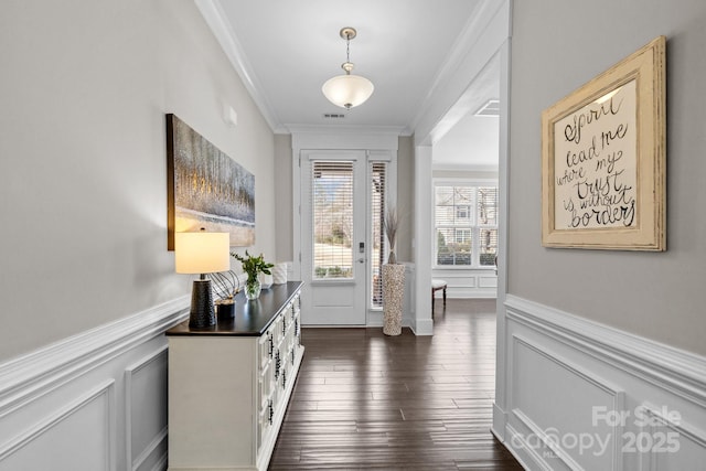 interior space featuring a decorative wall, a wainscoted wall, dark wood-style flooring, and ornamental molding