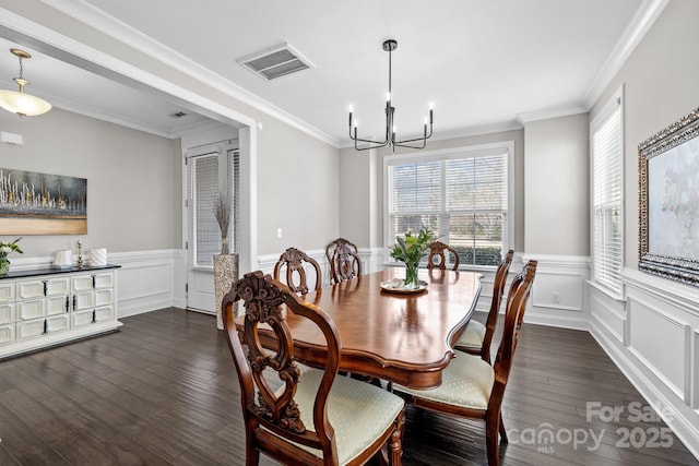 dining space featuring a wainscoted wall, visible vents, dark wood finished floors, ornamental molding, and a notable chandelier