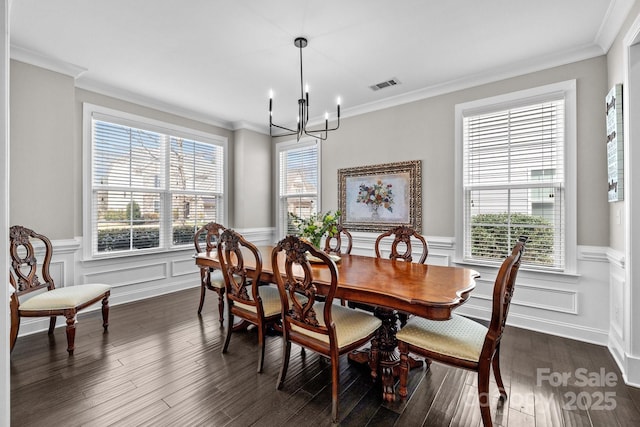 dining area with visible vents, crown molding, a chandelier, a wainscoted wall, and dark wood-style floors