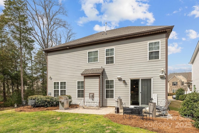 back of property with a lawn, roof with shingles, and a patio area