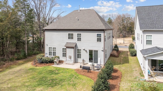 rear view of house with a patio, a lawn, and roof with shingles