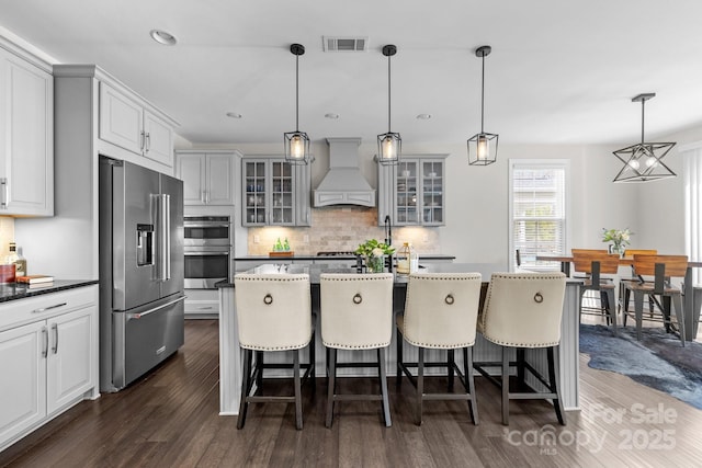 kitchen featuring visible vents, backsplash, dark wood finished floors, appliances with stainless steel finishes, and custom exhaust hood