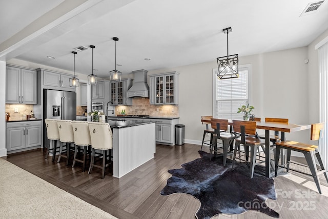 kitchen with visible vents, gray cabinets, custom range hood, dark countertops, and stainless steel appliances