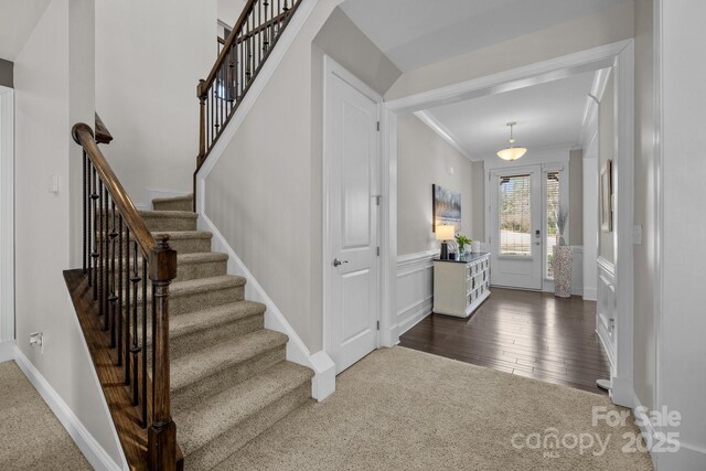 entryway featuring stairs, crown molding, and dark wood-type flooring