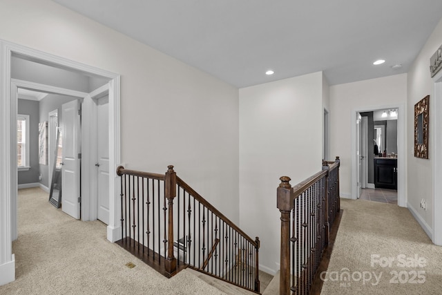 corridor featuring recessed lighting, baseboards, an upstairs landing, and light colored carpet