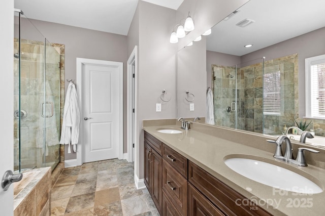 bathroom featuring double vanity, a stall shower, and a sink