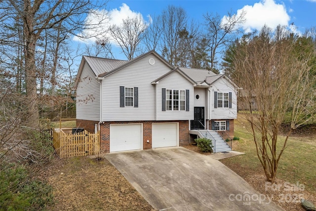 bi-level home featuring brick siding, concrete driveway, metal roof, and a garage