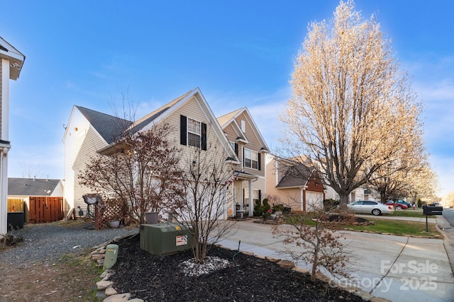 view of side of home featuring central AC unit, concrete driveway, and fence