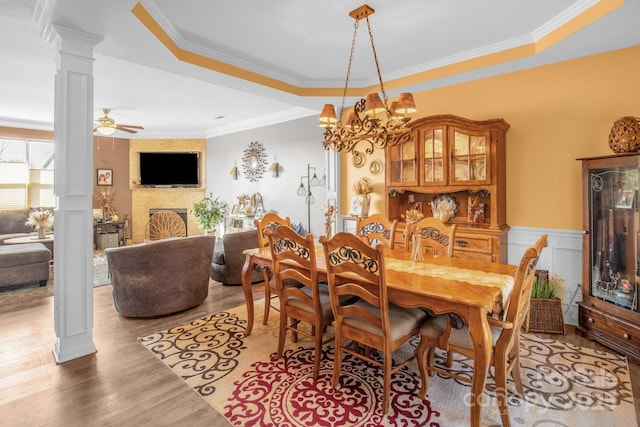 dining space featuring decorative columns, crown molding, wainscoting, and light wood finished floors