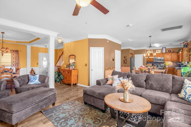 living room featuring light wood finished floors, visible vents, ceiling fan with notable chandelier, and ornamental molding