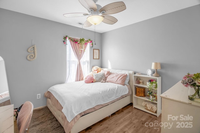 bedroom featuring visible vents, a ceiling fan, and wood finished floors