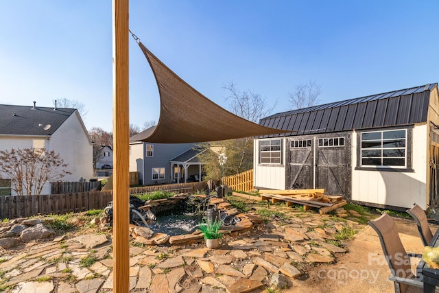 rear view of property featuring an outbuilding, a storage unit, fence, and metal roof