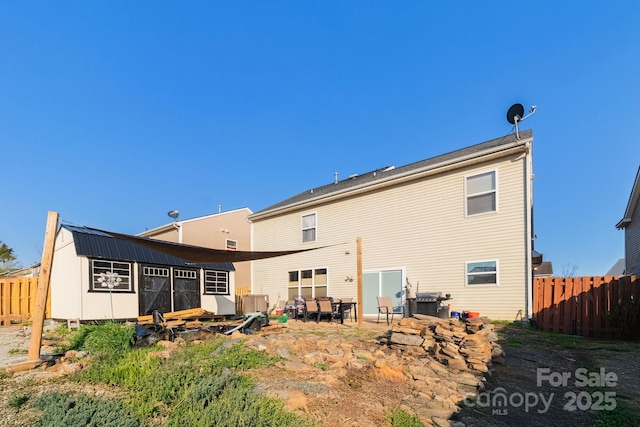 rear view of property with an outbuilding and fence