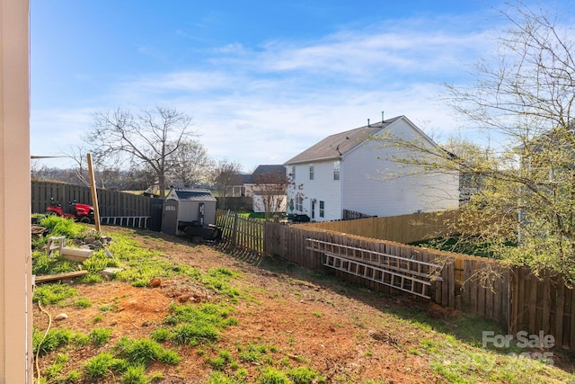 view of yard featuring a storage shed, a garden, a fenced backyard, and an outdoor structure