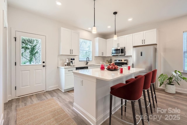 kitchen with a sink, stainless steel appliances, decorative backsplash, and white cabinetry