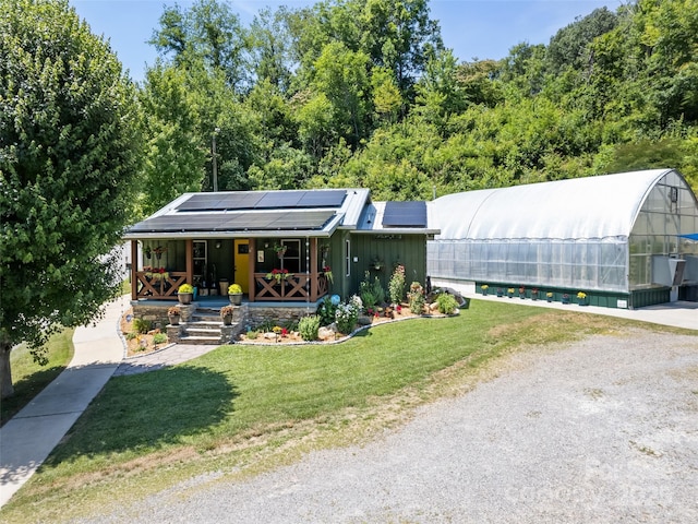 view of front facade with solar panels, a front lawn, covered porch, and an exterior structure