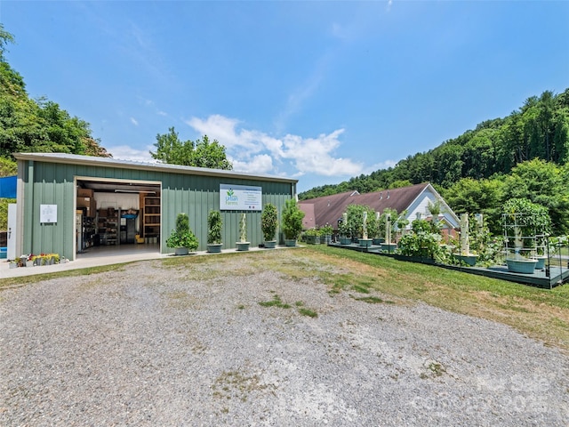 view of front of house featuring gravel driveway, a detached garage, board and batten siding, and an outdoor structure