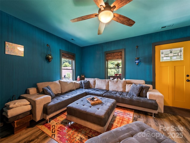 living area with visible vents, ceiling fan, and wood finished floors