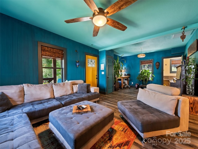 living area featuring baseboards, ceiling fan, and wood finished floors