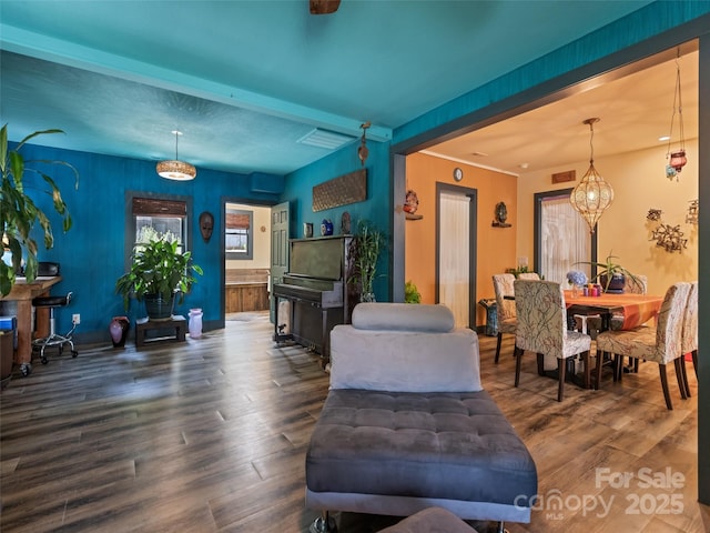 living room featuring beamed ceiling, a notable chandelier, visible vents, and wood finished floors