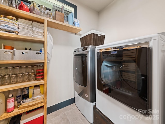 washroom with laundry area, washing machine and dryer, baseboards, and tile patterned floors