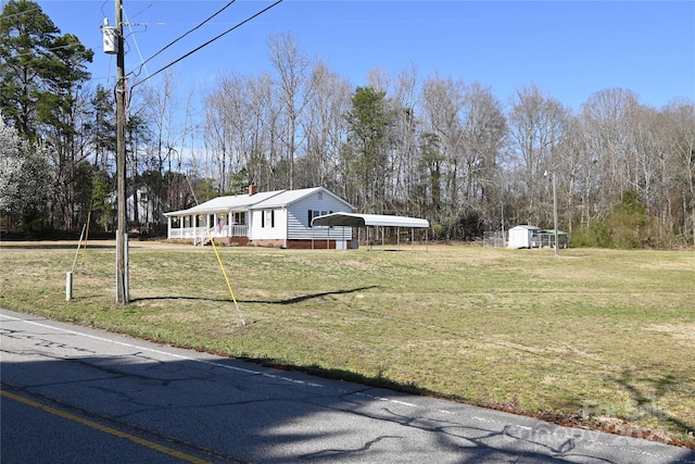 view of property exterior with a carport, an outbuilding, a lawn, and a chimney