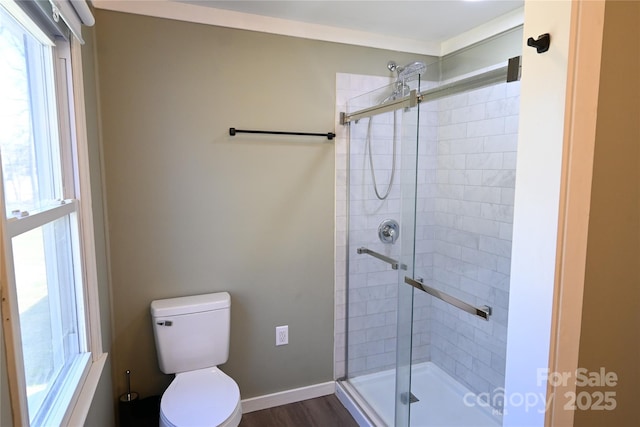 full bathroom with a stall shower, toilet, baseboards, and wood finished floors