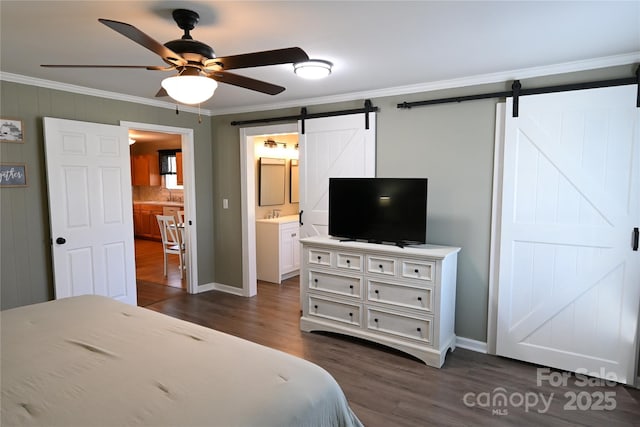 bedroom featuring a barn door, ornamental molding, ensuite bath, a ceiling fan, and dark wood-style flooring