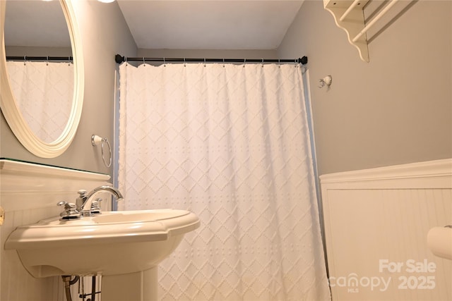 full bathroom with a sink and a wainscoted wall