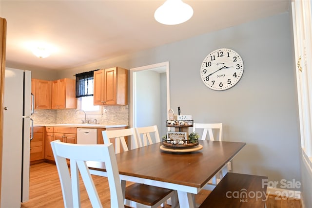 kitchen featuring light brown cabinetry, a sink, light countertops, tasteful backsplash, and light wood-type flooring