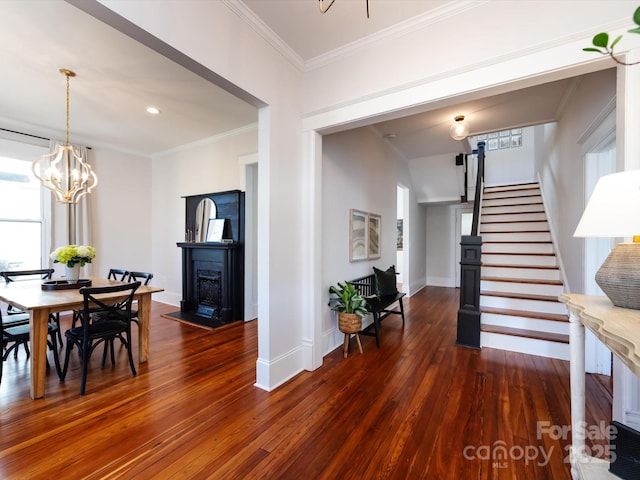 dining area featuring crown molding, baseboards, dark wood-type flooring, stairway, and a fireplace