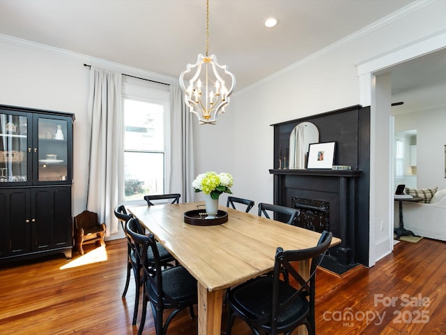 dining room featuring a chandelier, wood finished floors, a fireplace, and crown molding