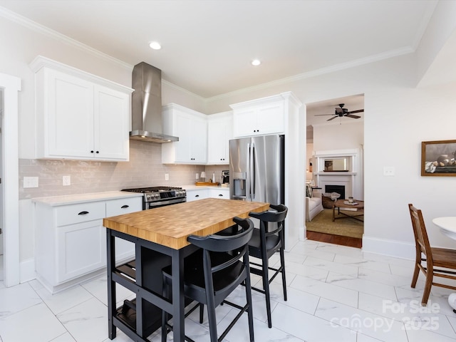 kitchen featuring stainless steel appliances, decorative backsplash, white cabinets, wall chimney range hood, and marble finish floor