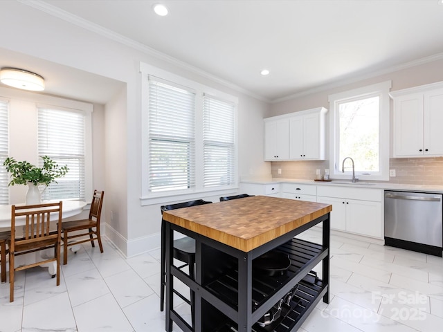 kitchen with tasteful backsplash, ornamental molding, light countertops, and stainless steel dishwasher