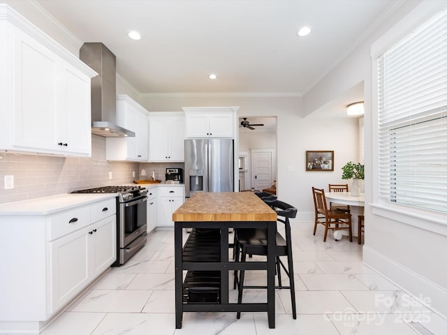 kitchen featuring crown molding, wall chimney exhaust hood, marble finish floor, and stainless steel appliances